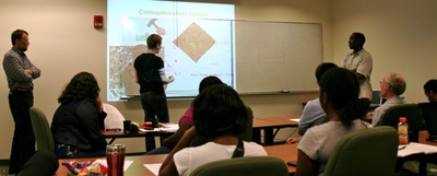 IGERT-MNM Trainee Tom Swisher (middle) approaches the board to explain his ideas during research presentation by NSU doctoral student John Kitur (right) while Prof. M. Noginov (left) looks on.